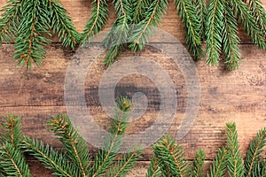 Christmas background with fir branches. Winter holidays frame with evegreen twigs on wooden board table.