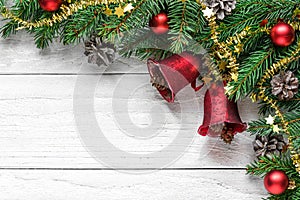 Christmas background with fir tree, christmas bells, berries, decorations and pine cones on white wooden table