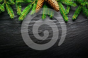 Christmas Background - Fir tree branch with pinecone on dark table. Top view and copy space