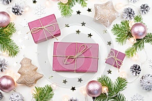 Christmas background with fir tree branches, purple giftboxes, Christmas lights, pink decorations, silver ornaments