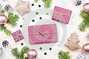Christmas background with fir tree branches, purple giftboxes, Christmas lights, pink decorations, silver ornaments