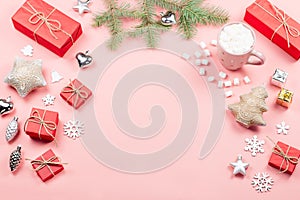 Christmas background with fir tree branches, red giftboxes, decorations, hot drink with marshmallows on pink