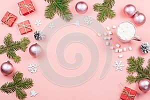 Christmas background with fir tree branches, red giftboxes, pink decorations, hot drink with marshmallows on pink