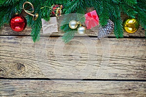 Christmas background with fir tree branches and traditional ornaments on a rustic wooden board.