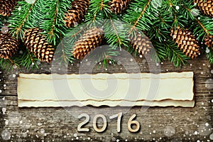 Christmas background of fir tree and conifer cone on old vintage wooden board, fantastic snow effect, wooden numbers of New year a