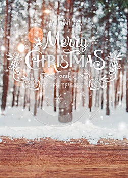 Christmas background with fir trees and blurred background of winter with text Merry Christmas and Happy New Year and wooden table