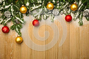 Christmas background with firtree and baubles on wood with snow