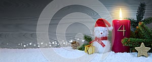Christmas background with fourth Advent candle and Snowman with red decoration.