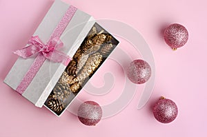 Christmas background. Gift box filled with golden cones and baubles, flat lay. Copy space