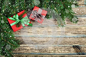 Christmas background with gift box and fir branch on wooden rustic board, festive snow effect, Christmas frame