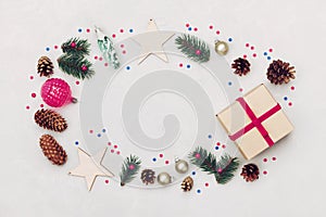 Christmas background of gift box, fir tree, conifer cone and holiday decorations on white table top view. Flat lay styling.