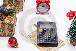 Christmas background with gift boxes, alarm clock, 50 euro banknote and calculator. Preparation for the winter holidays. It`s tim