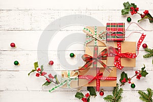 Christmas background with gift boxes, Christmas decorations and branches of holly and fir on white wooden background. Winter