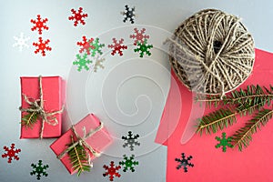 Christmas background with gift boxes, clews of rope, paper and decorations on red. Preparation for holidays