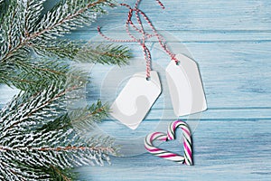 Christmas background, gift tags and candy canes in a heart shape, wooden background with fir tree branch