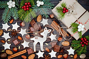 Christmas background with gingerbread cookies, presents, fir branches and spices on the old wooden board