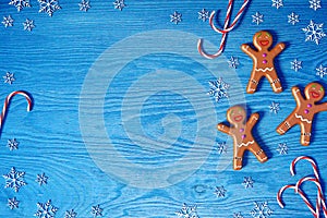 Christmas background. Gingerbread man, Christmas candy cane and snowflakes on blue wooden background with copy space for text.