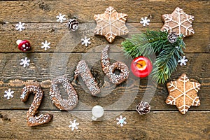Christmas background with gingerbread numbers 2016, fir branches and decorations on the old wooden board.