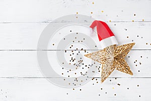 Christmas background of golden star with Santa hat and confetti top view. Flat lay.