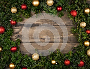 Christmas background with green branches and christmas balls on the rustic wooden background