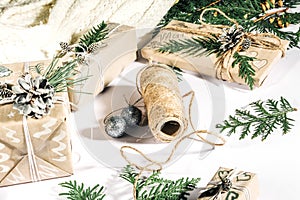 Christmas background with handmade gift boxes, clews of rope and decorations with pine cones and twigson white