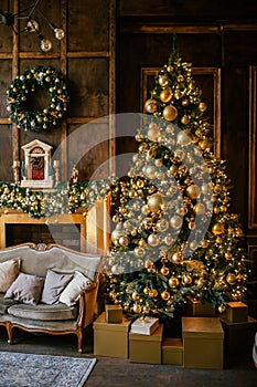 Christmas background with illuminated fir tree with golden decpration and fireplace in living room. Cozy holiday home