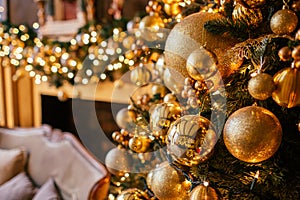 Christmas background with illuminated fir tree with golden decpration and fireplace in living room. Cozy holiday home, close up