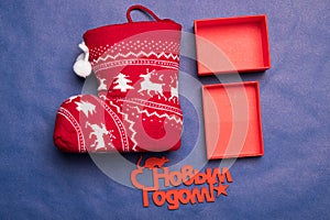 Christmas background with the inscription in Russian New Year`s studio image. Red gift box with christmas sock on a blue backgroun