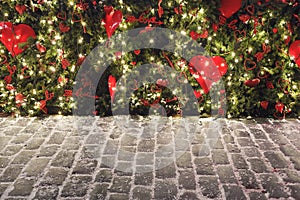 Christmas background with lights on pine, red love hearts and stone paving