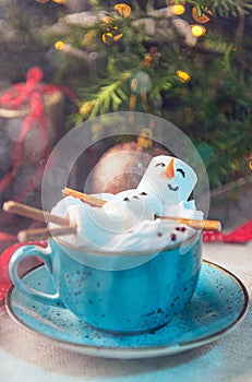 Christmas background with a marshmallow man lying in a mug with cocoa, in the background a Christmas tree with toys, a garland and