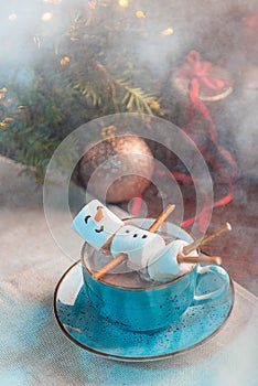 Christmas background with a marshmallow man lying in a mug with cocoa, in the background a Christmas tree with toys, a garland and