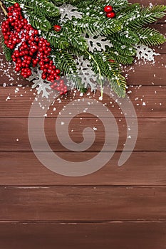 Christmas background. New Year fir tree, dog rose, fresh leaves and artificial snow. Wooden boards backdrop