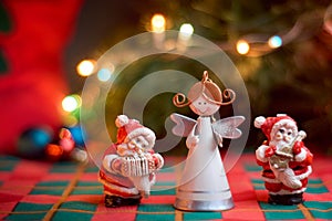 Christmas background with ornaments on table. Miniature figures of angel and Santa Claus playing musical instruments. Christmas