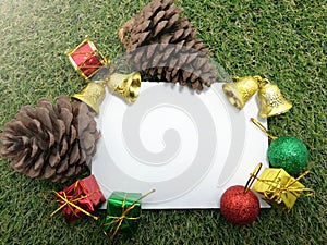 Christmas background pine cone gift boxes, bells and space for writing your message on green grass.