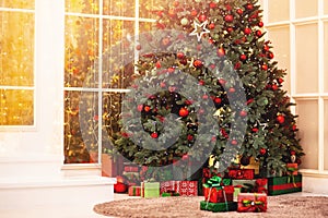 Christmas background pine tree branch with decorations red balls gifts and star, with sun light