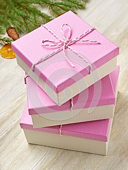 Christmas background. Pink boxes on white wooden background fir-tree branches, Christmas toys, Christmas tree, snowflake, orange