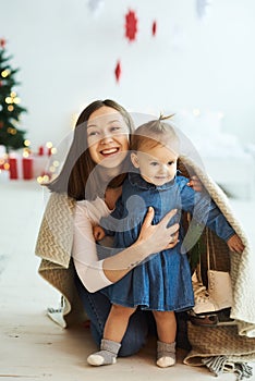 Christmas background. Portrait of happy mother and her daughter having fun and covered with blanket