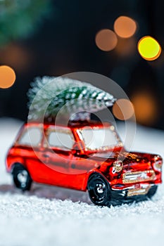 Christmas background preparing for the New year. Christmas tree on the roof of a car traveling in the snow on a blurred bokeh