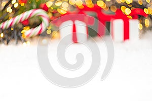 Christmas background with presents, gist boxes with red ribbon, candy stick and Christmas tree and bokeh of golden