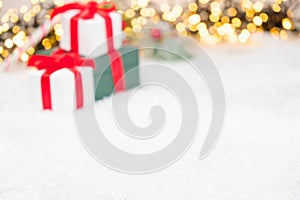 Christmas background with presents, gist boxes with red ribbon, Christmas tree and bokeh of golden lights with copy
