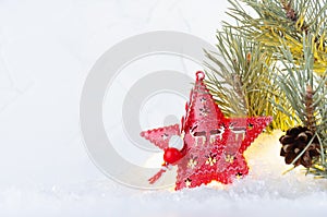 Christmas background with red  christmas star with lights glowing inside and pine green branch in bright shimmer snow, copy space.
