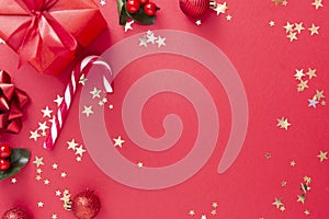 Christmas background, red gift box on red background and golden sparkling conffeti, candy cane