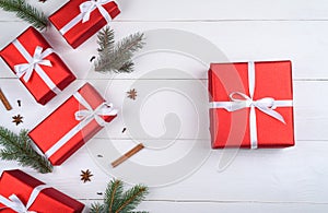 Christmas background with red gift boxes, fir tree branches, pine cones, cinnamon sticks and stars anise on white wooden.