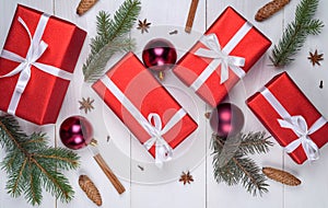 Christmas background with red gift boxes, fir tree branches, pine cones, cinnamon sticks and stars anise. Christmas gift boxes.