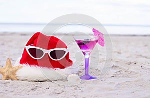 Christmas background Santa Claus hat on the beach with starfish,cocktail and sunglases
