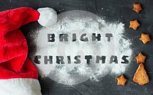 Christmas background with Santa's cap and baked gingerbread stars and christmas tree with words bright christmas made