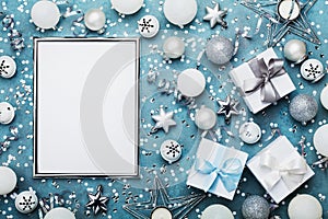 Christmas background. Silver frame with xmas decoration, gift box, confetti and sequins on vintage blue table top view. Flat lay.