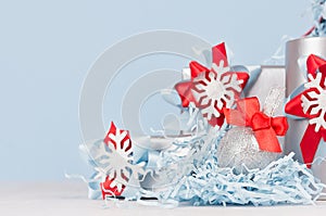 Christmas background - silver glittering ball with red silk bow closeup, blur and decorations on soft light blue color backdrop.