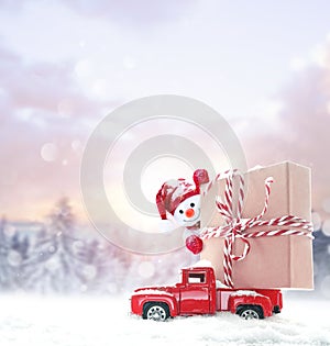 Christmas background with snow, snowman and retro red car with gift box. Merry Christmas and happy New Year.