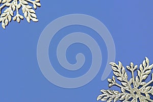 Christmas background with snowflakes. On a blue background two silver-white snowflakes with sparkles are laid out. Happy